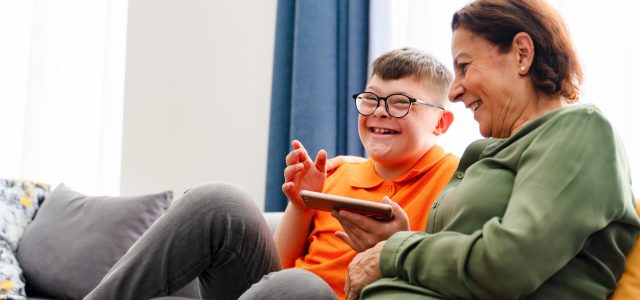 Little boy with down syndrome enjoy spending time with mother and watching mobile phone