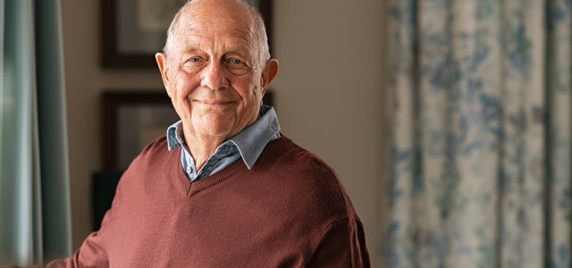 Happy senior man looking at camera at home